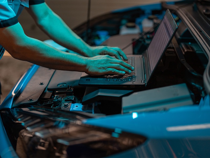 Ein Techniker von Jäckle Automobile arbeitet mit einem Laptop im geöffneten Motorraum eines Autos an dessen Software.