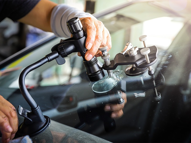 Ein Techniker von Jäckle Automobile repariert einen Steinschlag auf der Windschutzscheibe mit modernen Geräten.