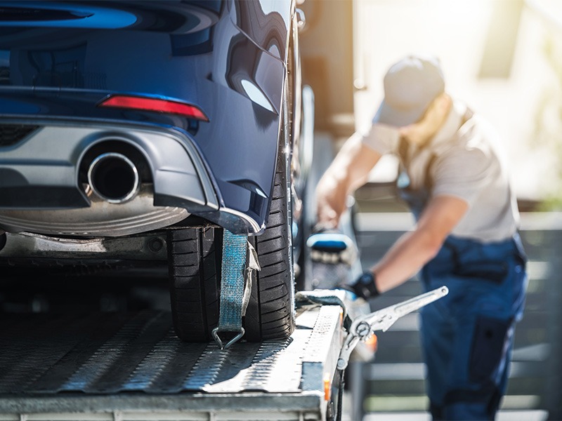 Ein Mann bereitet ein Auto vor um es in die Werkstatt zu transportieren.