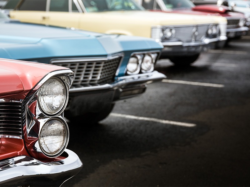 Mehrere gepflegte Oldtimer in verschiedenen Farben stehen nebeneinander.