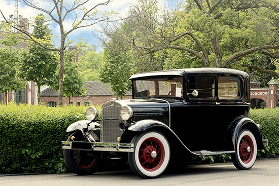 Ei schöner schwarzer Oldtimer steht vor einem Park.