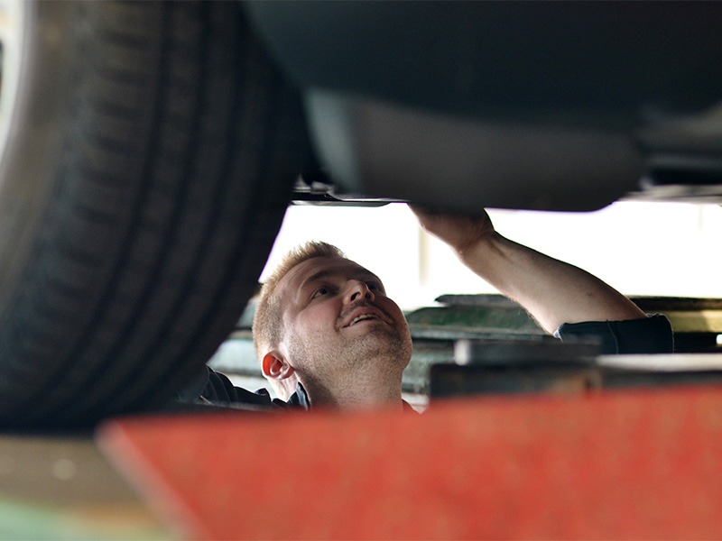 Ein Techniker von Jäckle Automobile arbeitet an der Unterseite eines Autos.