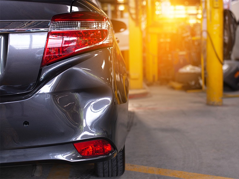 Ein Auto hat hinten eine große Delle nach einem Unfall.