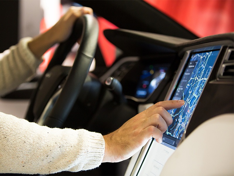 Der Fahrer bedient das eingebaute Navi eines modernen Wagens.