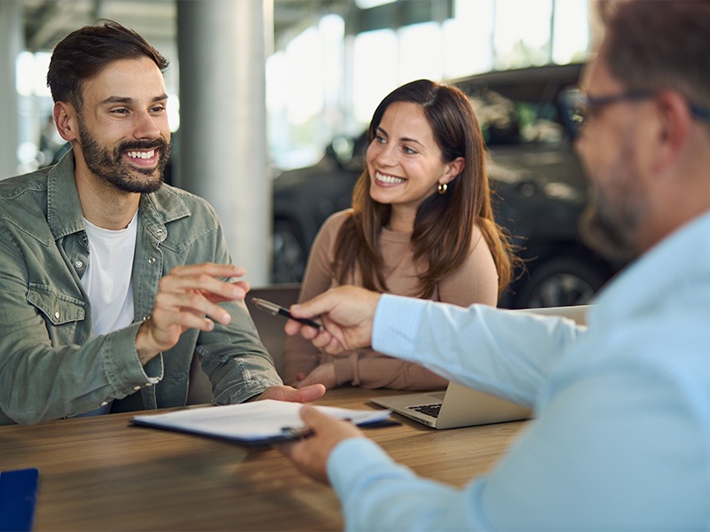 Junges Paar freut sich und unterschreib einen Kaufvertrag für ein Auto bei Jäckle Automobile.
